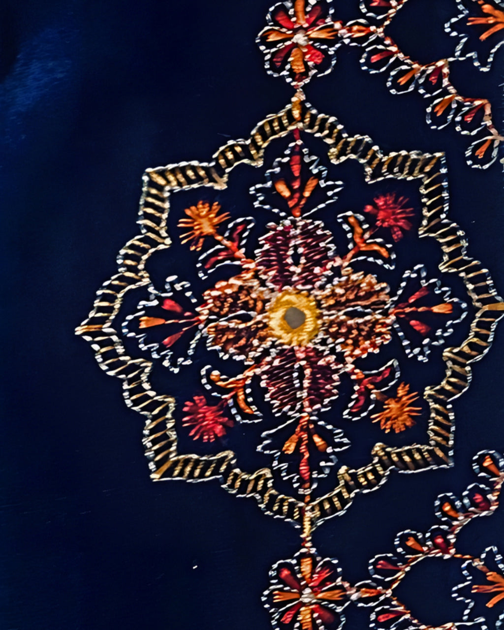 Détail des motifs brodés dorés, rouges et orangés sur le velours bleu profond