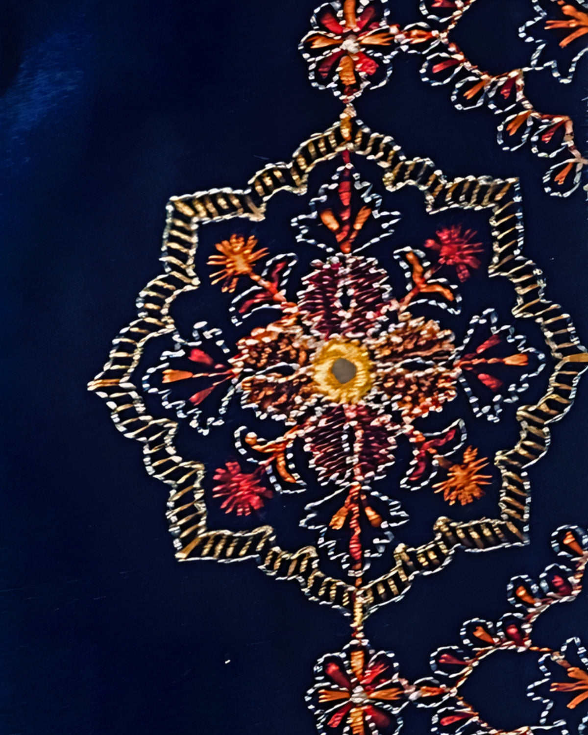 Détail des motifs brodés dorés, rouges et orangés sur le velours bleu profond