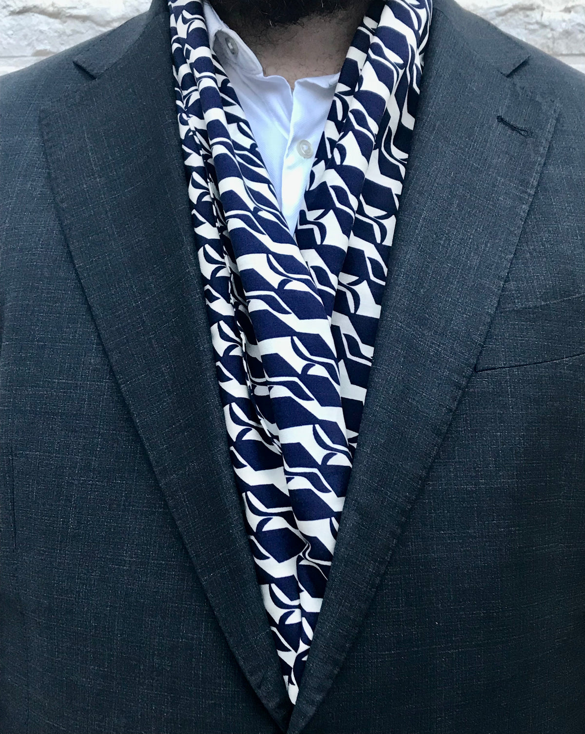Écharpe crème à motifs géométriques bleu foncé portée avec un costume