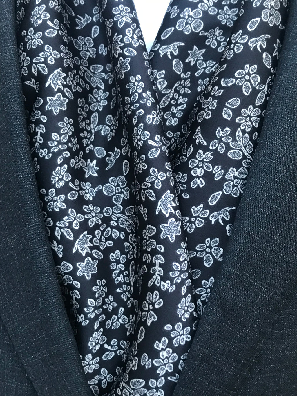 Détail des motifs floraux blancs sur l’écharpe noire