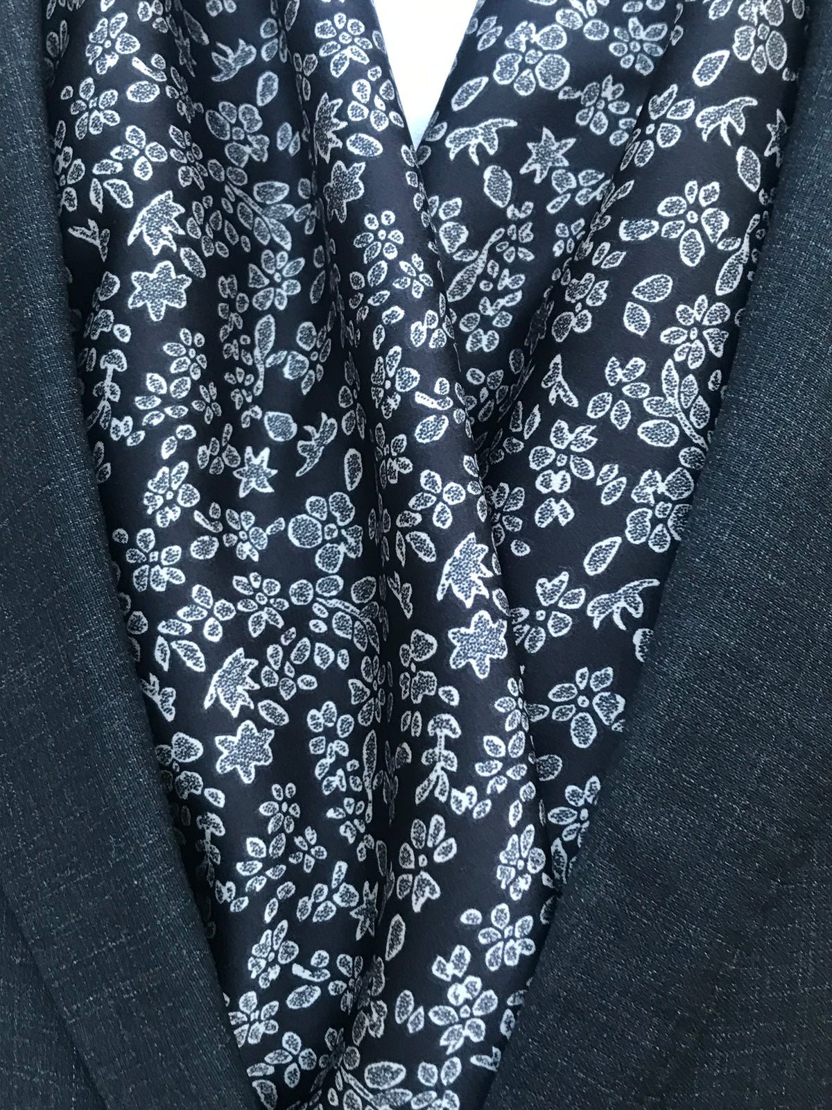 Détail des motifs floraux blancs sur l’écharpe noire